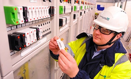 PPL utility worker in a hard hat examining objects