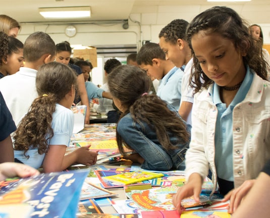 A group of students around a table selecting books