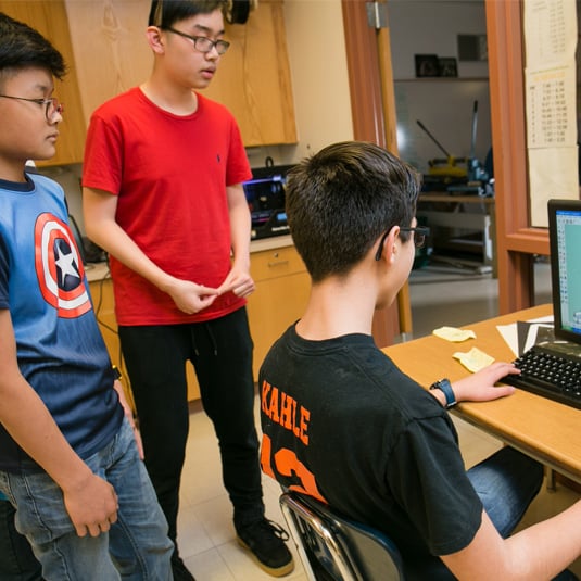 Three students around a computer