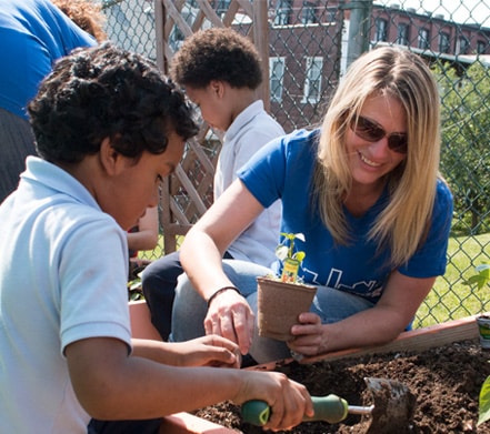 A PPL employee helping a child plant flowers in a garden