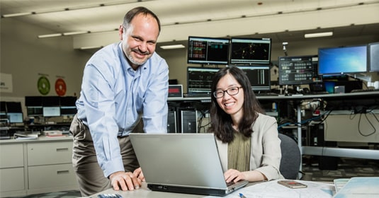 A female PPL employee using a computer and a male coworker collaborating