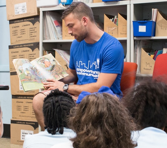 A male PPL employee reading a book to children