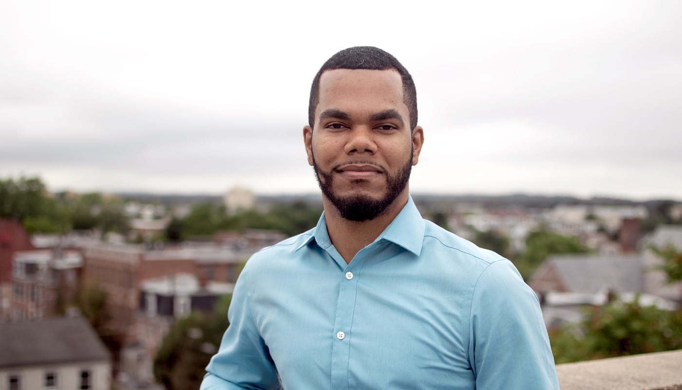 A young Black male stands outside with a view of Allentown behind him.