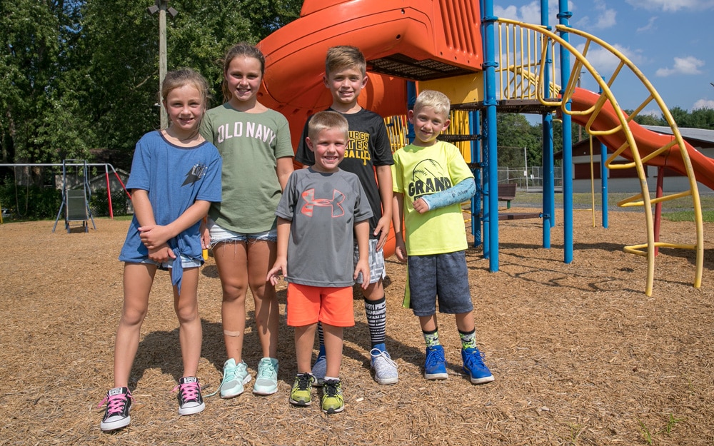 A group of children happily pose in front of playground equipment at a park that PPL revitalized...