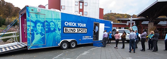 PPL employees lined up in parking lot outside a blue-green trailer on a cloudy day