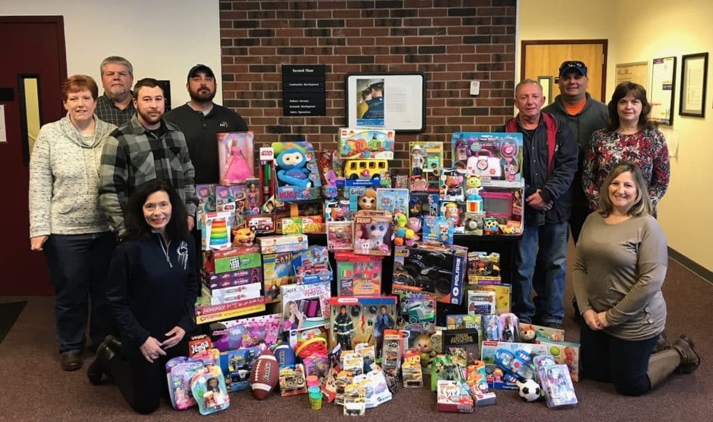 Employees gather in office setting posed with colorful toys and books for donation