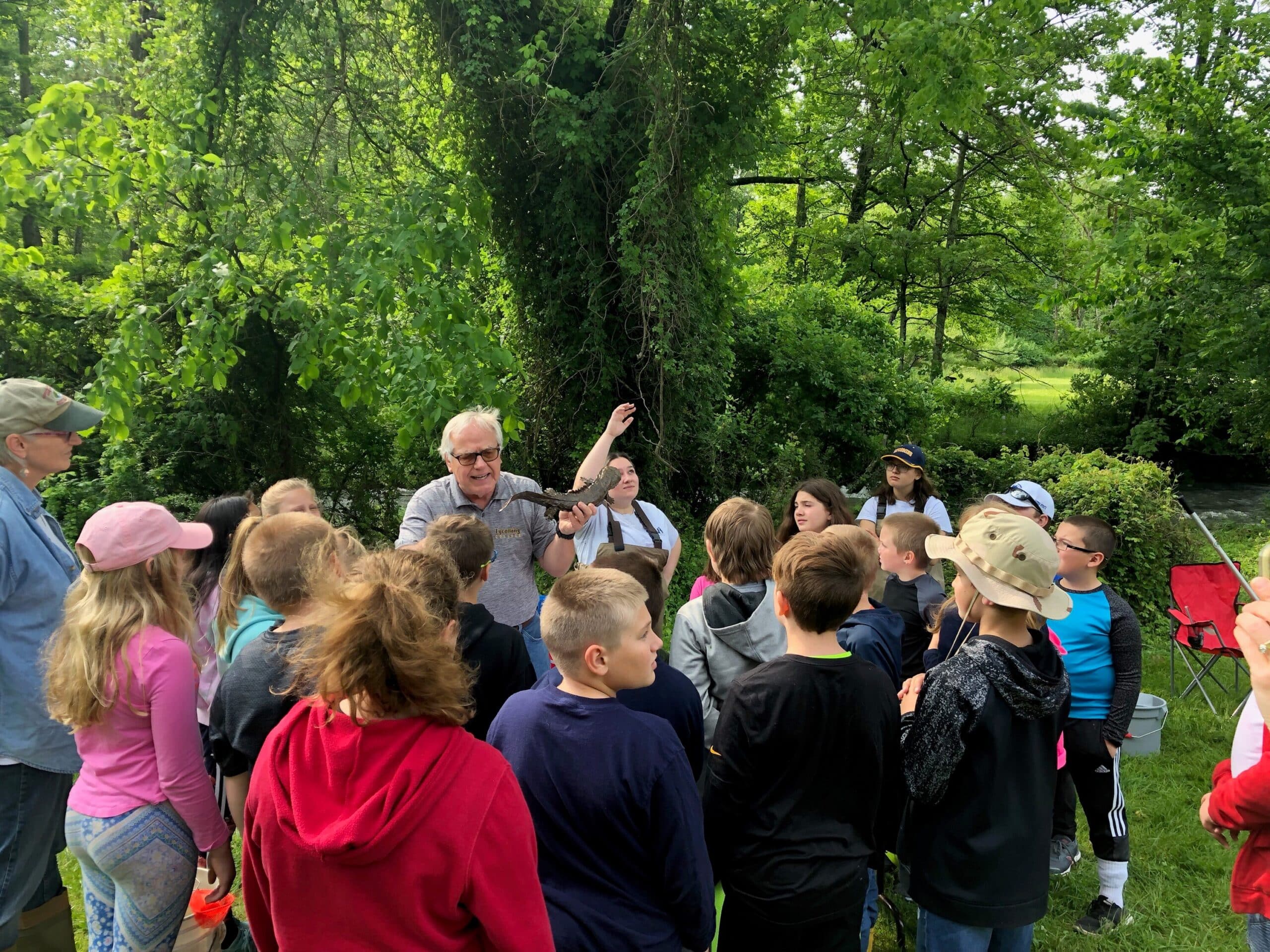 A man teaches a group of school children about birds of prey in an outdoor setting