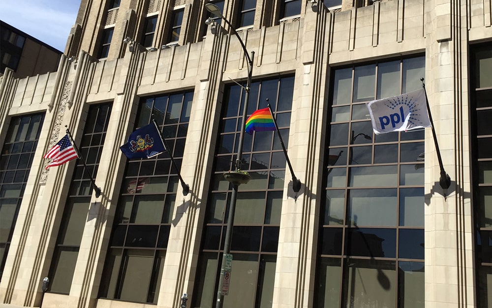 Photo of outside of PPL Tower with four flags flying -- PPL flag, LGBTQ Pride flag, Pennsylvania...