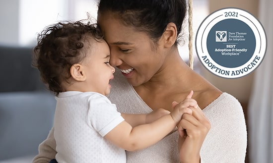 Smiling female holding baby with adoption advocate emblem on the image