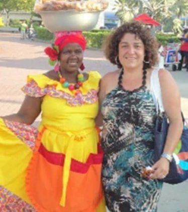 Columbian woman poses with a brown-skinned woman in traditional Colombian dress.